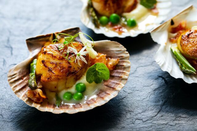 Jakobsmuscheln mit Blumenkohlpüree, Pancetta, grünen Erbsen und Microgreens