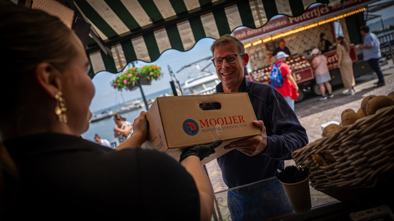 medewerker van mooijer die persoonlijk een bestelling aflevert bij een klant op de welbekende volendammer dijk.