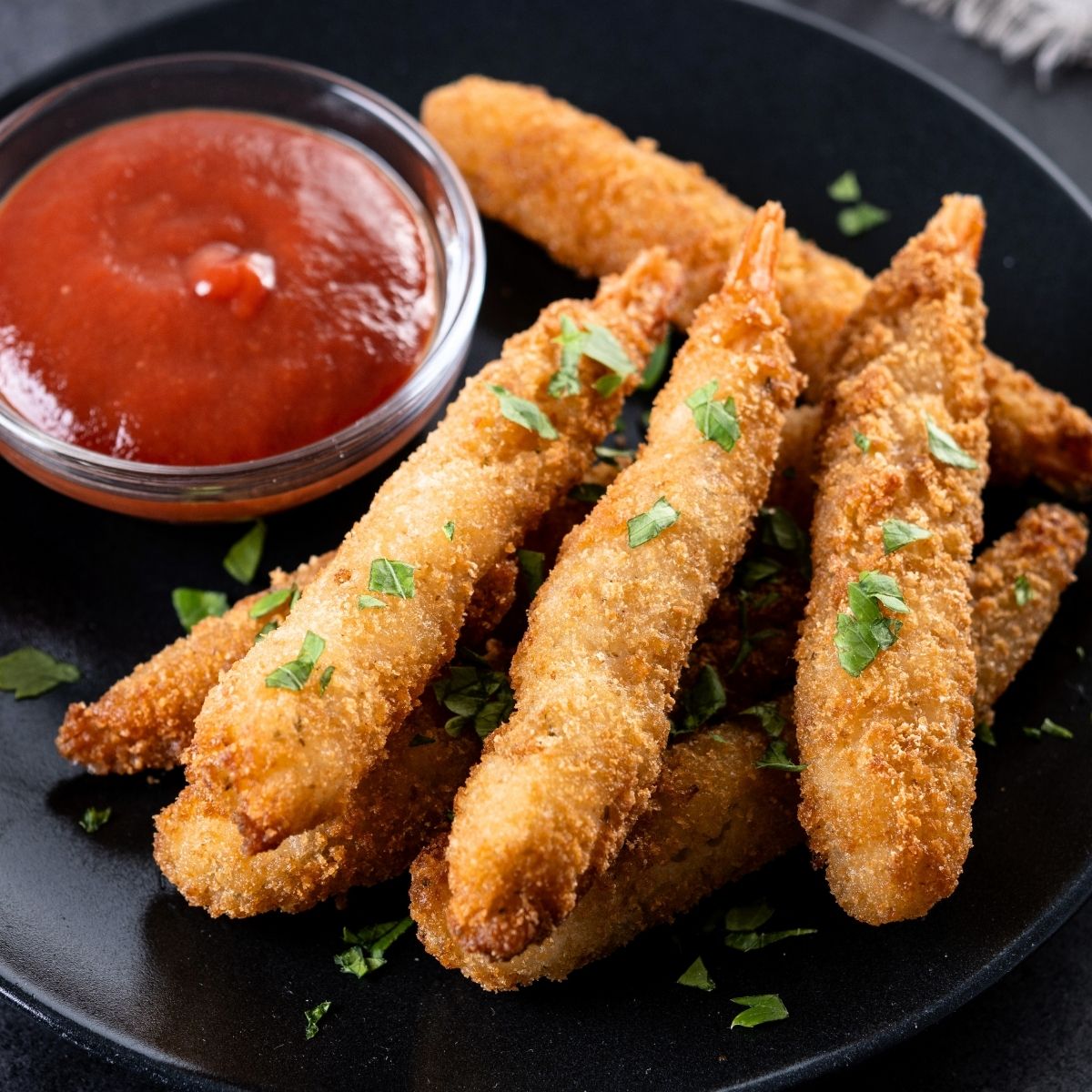 Krokant gebakken torpedo garnalen met een pittige saus en wat peterselie.